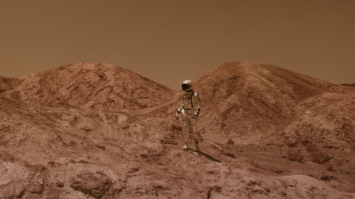 Astronaut in spacesuit explores barren, Mars-like desert terrain under brown sky