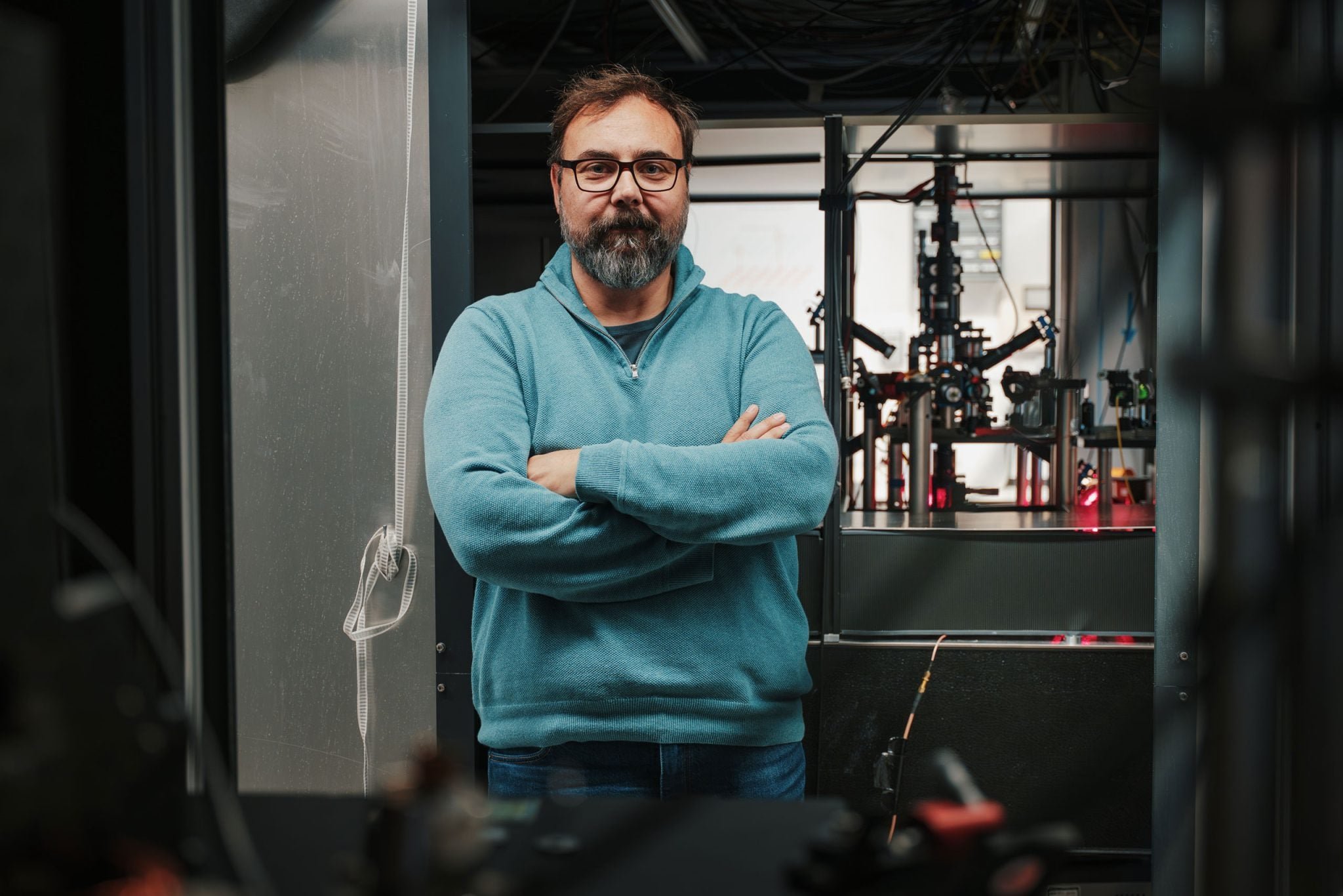Giovanni Barontini, Professor of Physics, at the University of Birmingham, with the apparatus to trap and cool rubidium atoms in the background
