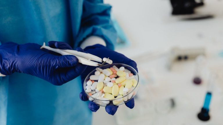Researcher handling pills in a petri dish for medicine testing