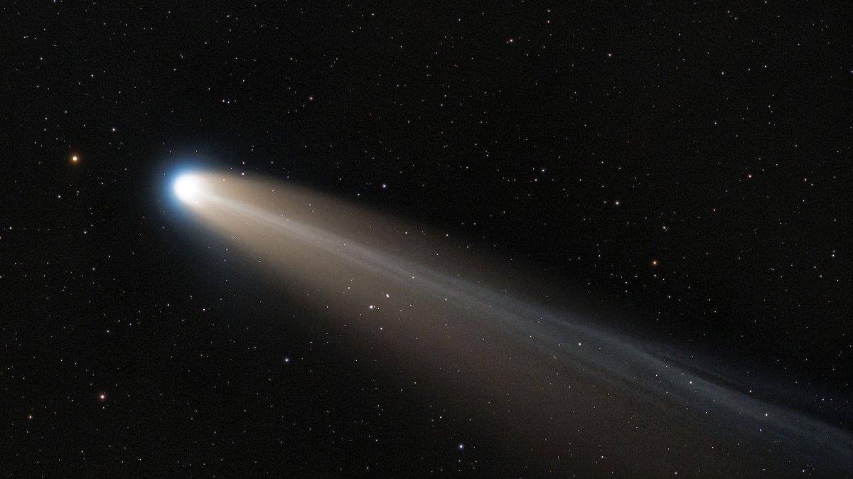 A bright comet streaks through the star-filled night sky, emitting a glowing tail