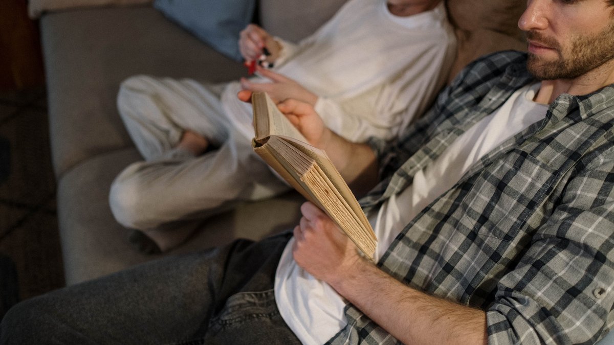 Father reading while his child plays nearby at home