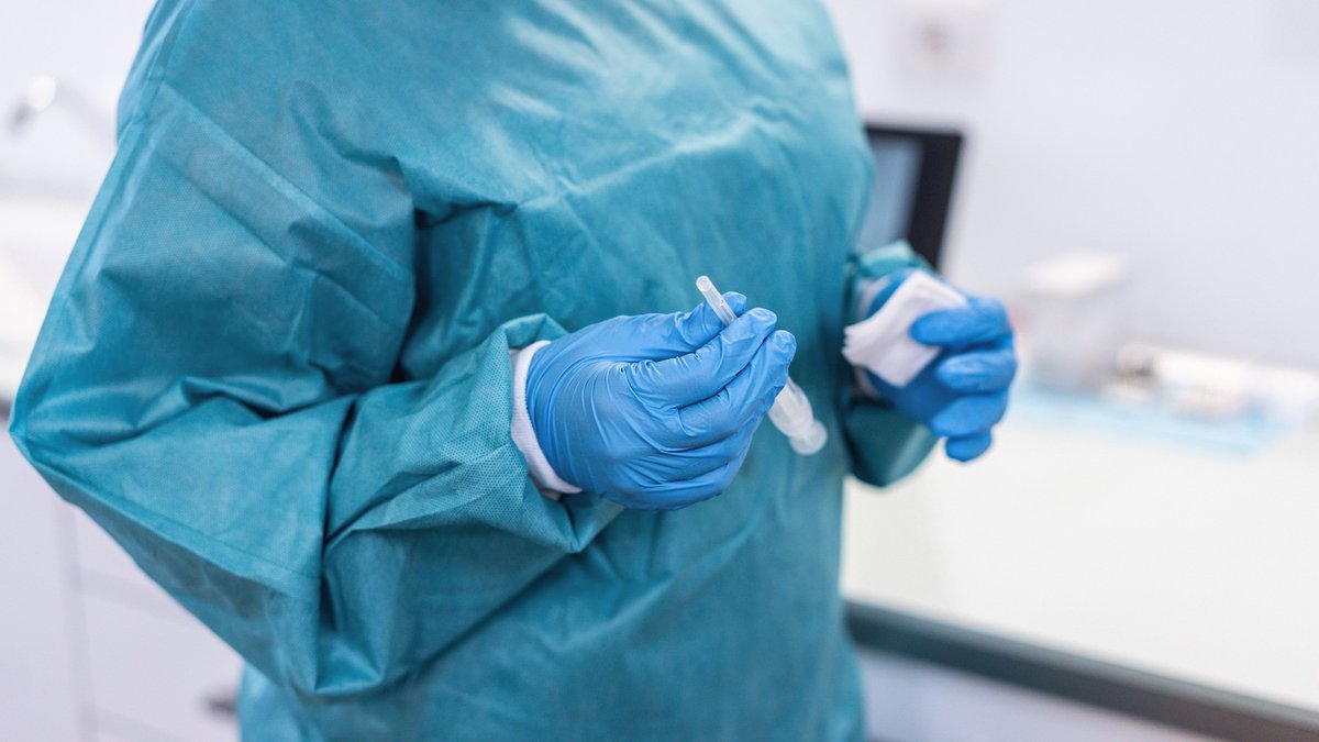 Medical doctor holding syringe with vaccine for coronavirus disease - Focus on right hand glove