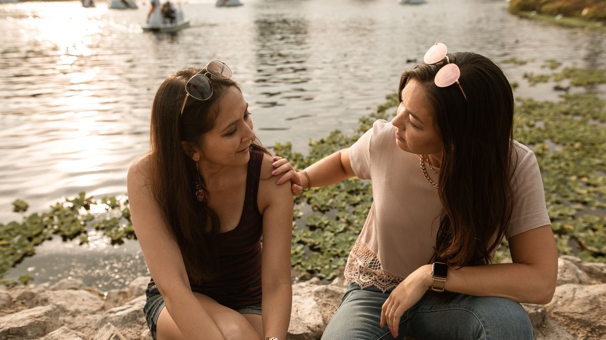 Two friends having a conversation by a lake