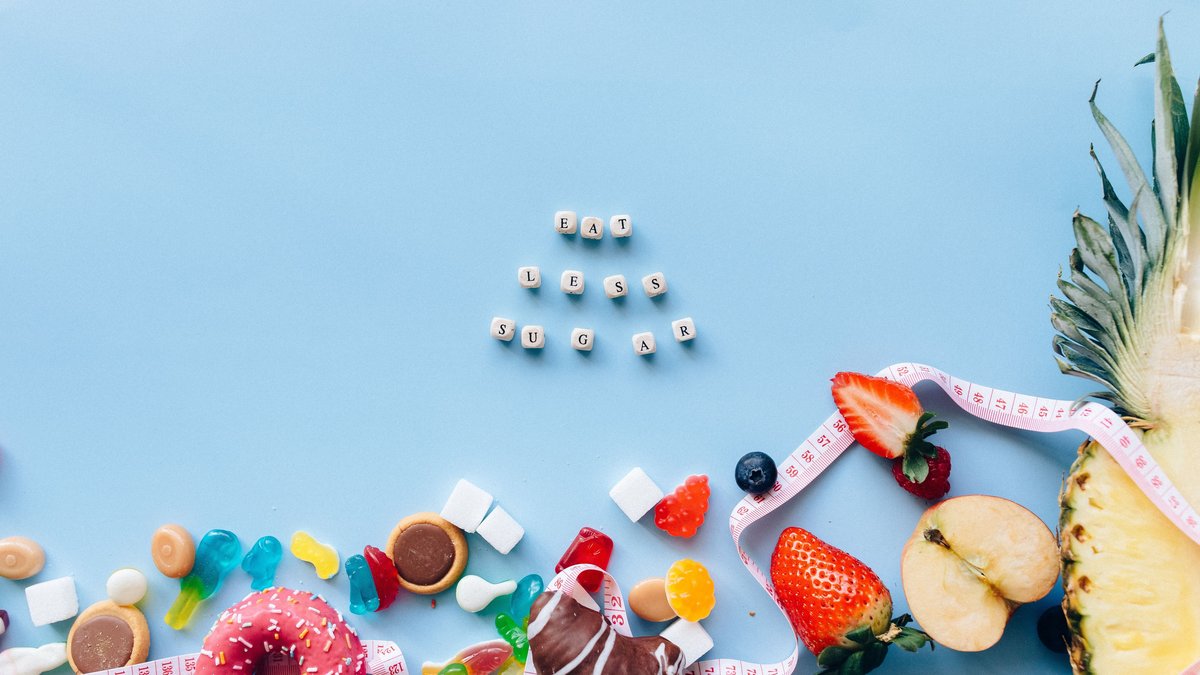 Juxtaposition of sugary sweets and fresh fruits with a message to eat less sugar