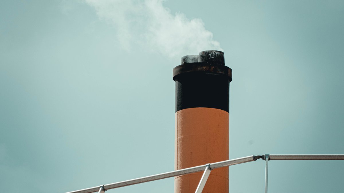 An industrial chimney releasing smoke into the sky, depicting pollution and emissions