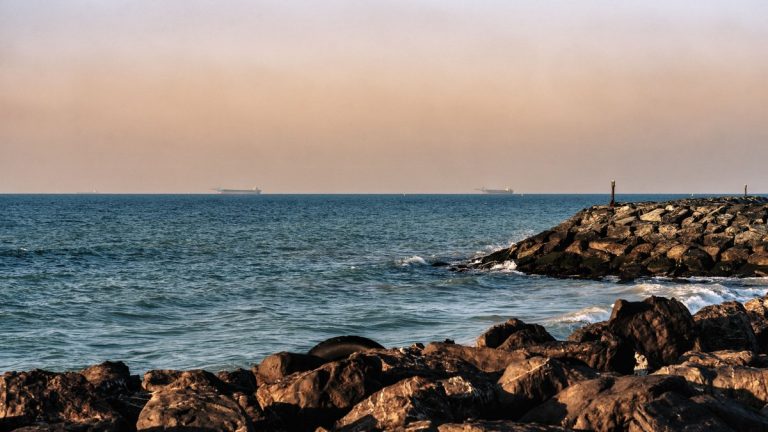Rocky Persian Gulf shoreline with cargo ships off Sharjah