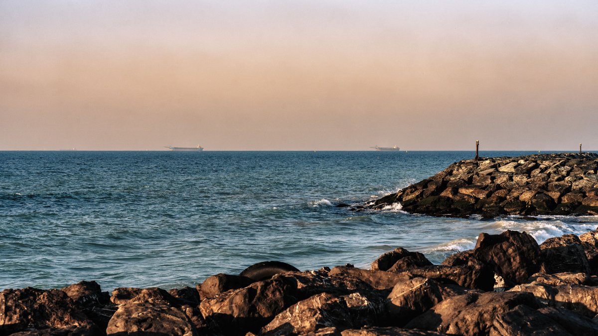 Rocky Persian Gulf shoreline with cargo ships off Sharjah
