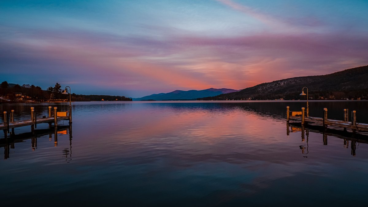 Wooden docks on Lake George beneath a colorful sunset
