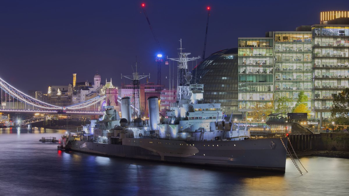 Illuminated HMS Belfast with Tower Bridge in the backdrop at night in London