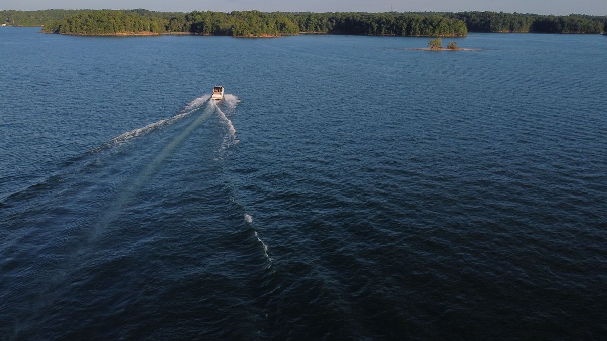 Captivating aerial view of a boat cruising on Lake Lanier surrounded by lush greenery in Georgia