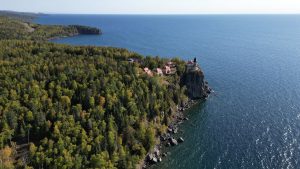 Majestic aerial view of Split Rock Lighthouse on a forested cliff overlooking Lake Superior.