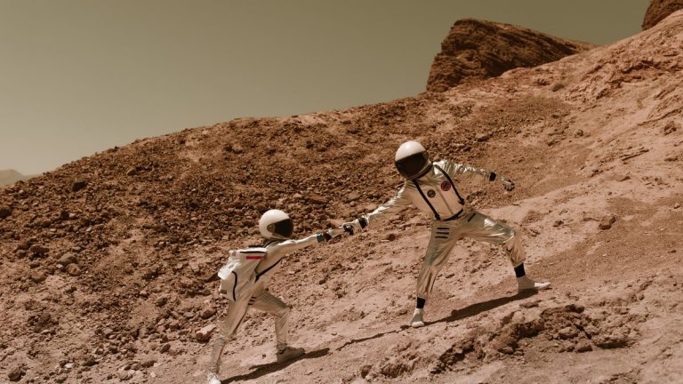 Astronauts moving across rocky Mars-like terrain