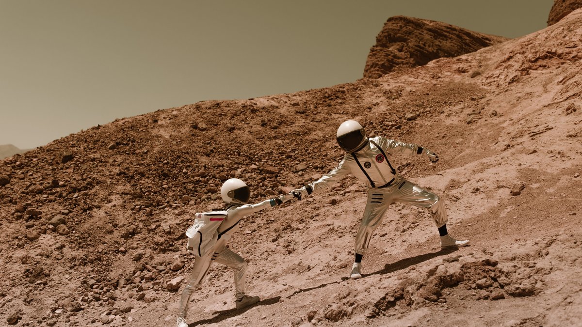 Astronauts moving across rocky Mars-like terrain
