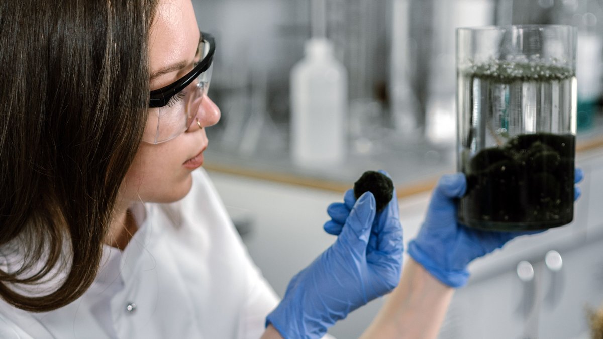 A scientist in a lab coat examines a sample with laboratory equipment