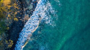 Aerial view of ocean waves meeting a rocky coastline