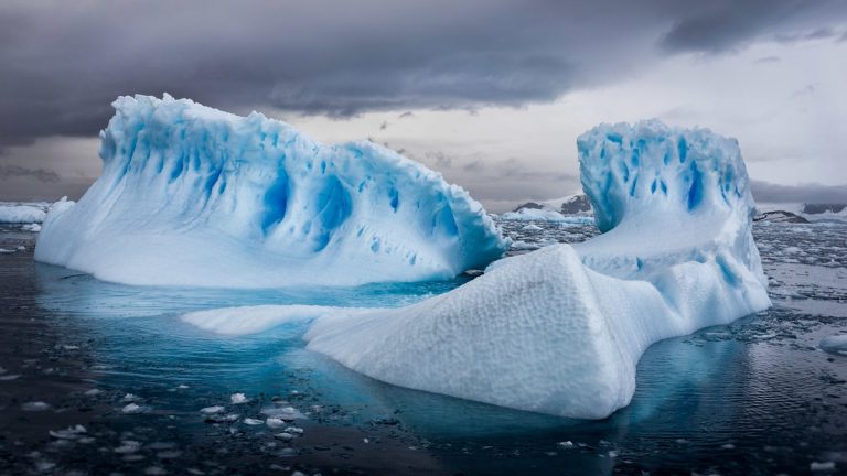 An aerial shot of icebergs in Antarctica under cloudy sky