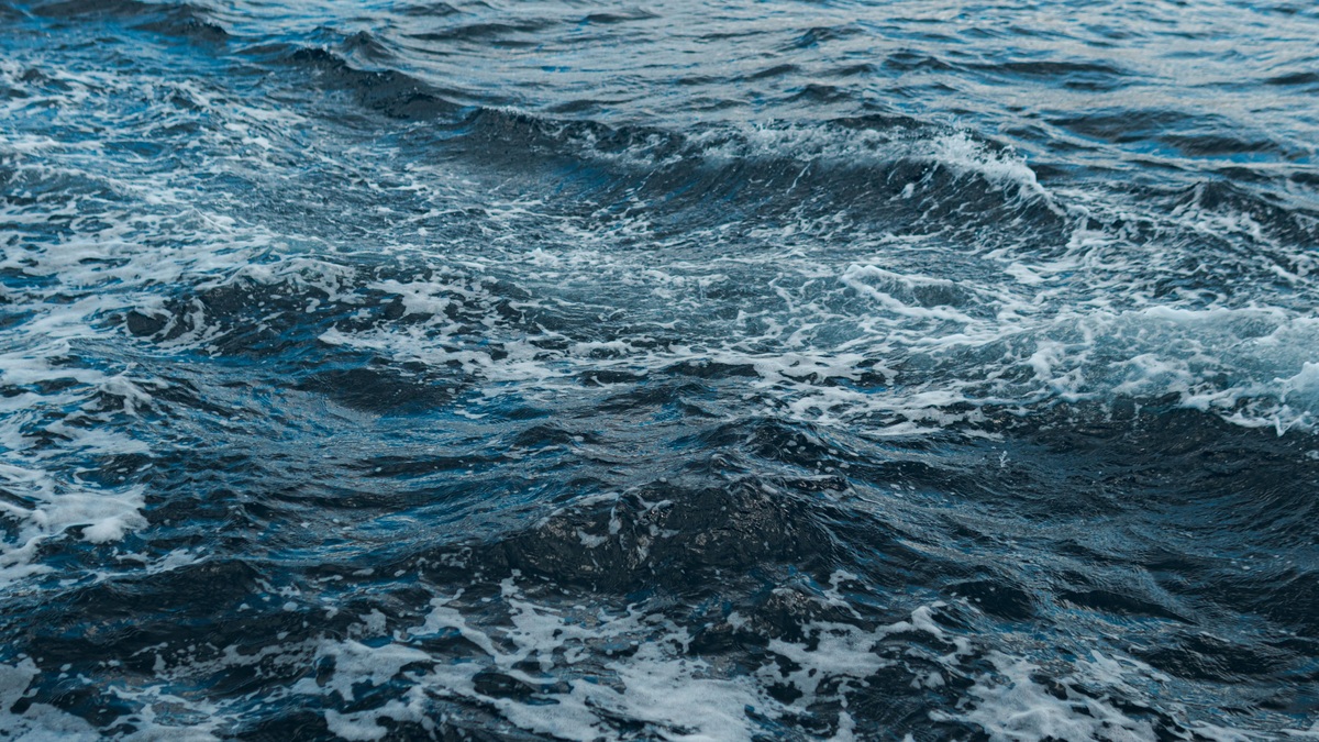 Close-up shot of swirling ocean waves and white foam, showing natural movement