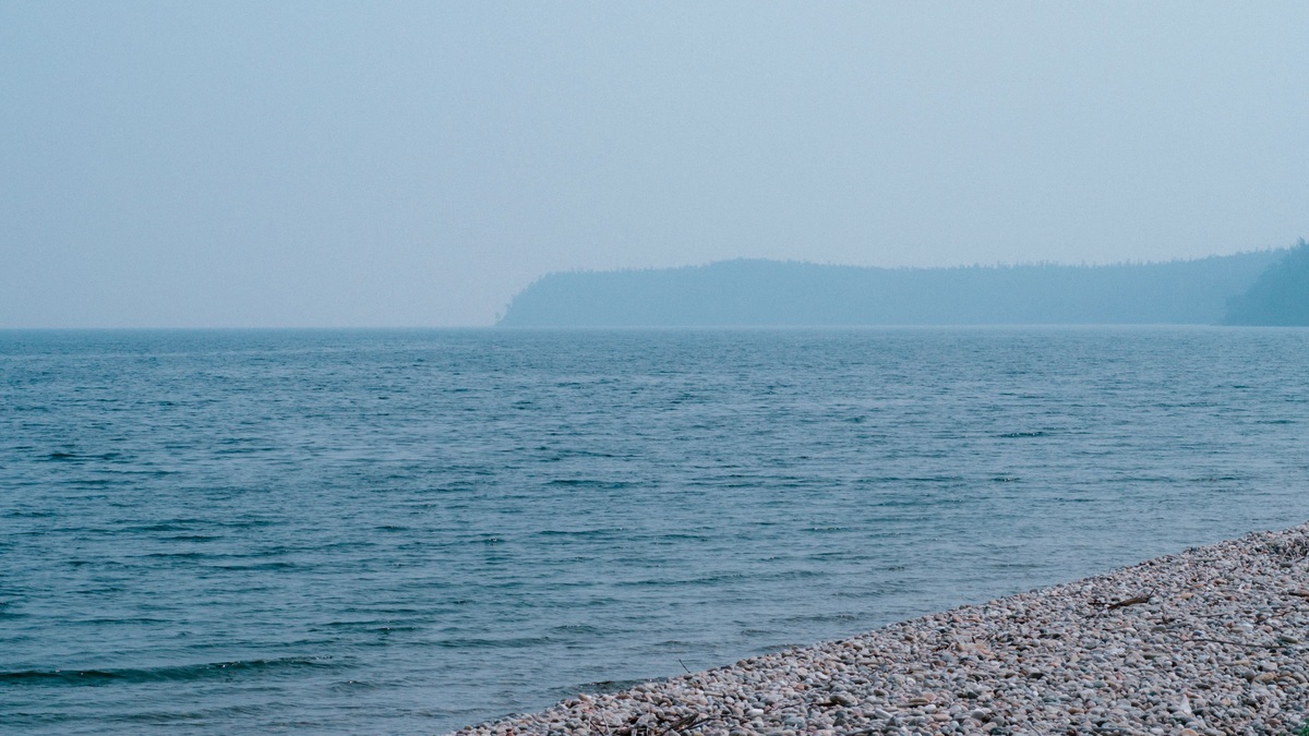 Peaceful view of Lake Baikal's shoreline with clear blue waters under a summer sky
