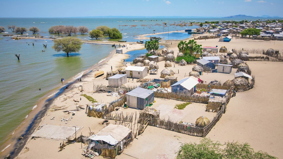 A scenic aerial view of Kalokol village by Lake Turkana in Kenya, showcasing traditional huts and a vibrant landscape