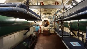 View of a submarine's bunk room with torpedo tubes and metal bunks