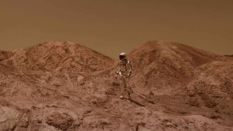 Astronaut in spacesuit explores barren, Mars-like desert terrain under brown sky
