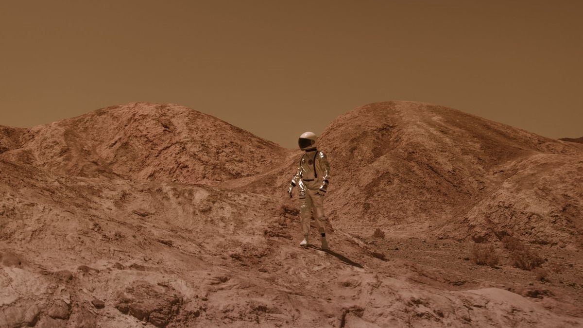 Astronaut in spacesuit explores barren, Mars-like desert terrain under brown sky