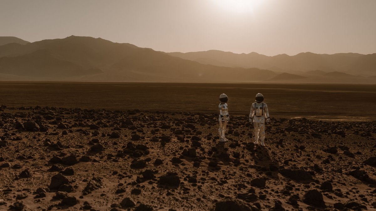 Two astronauts exploring a rocky Mars-like landscape