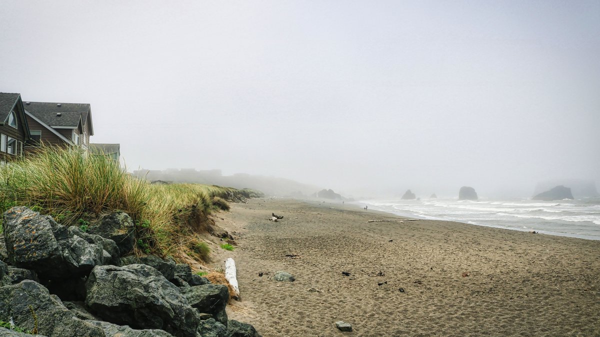 Serene foggy beach scene on the Oregon coast with sea stacks and nearby coastal homes