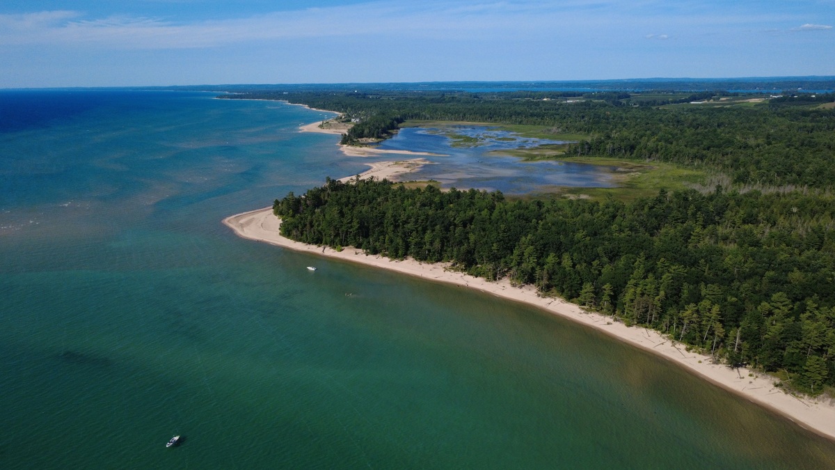 Drone shot of Michigan's coastal landscape with lush forests and clear waters in summer