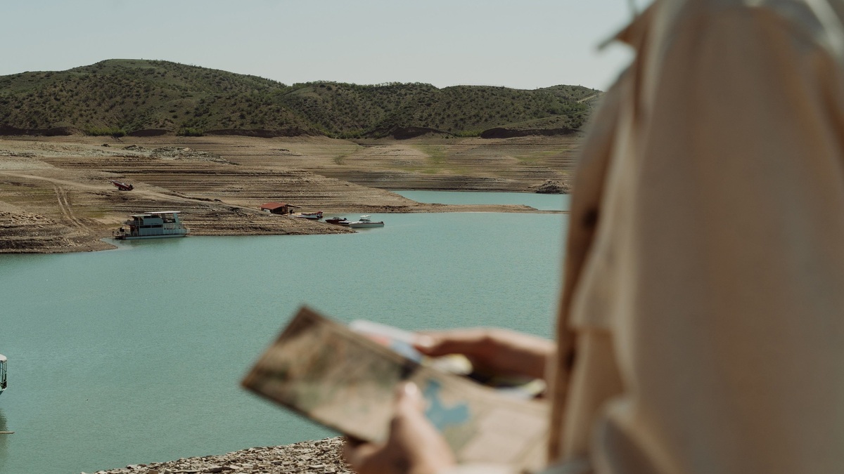 Traveler studies map by tranquil lake surrounded by hills
