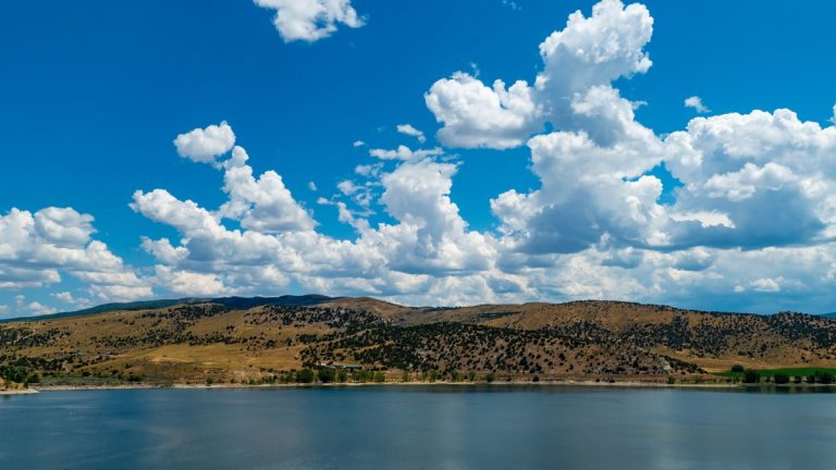 Beautiful landscape of a lake with hills and mountains under a vibrant blue sky in Utah