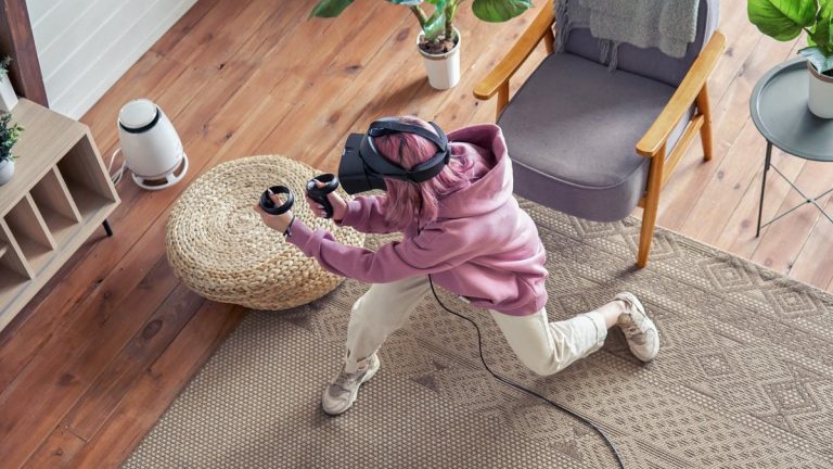 Teen girl pink hair wear vr headset goggles hold controllers play active shooter vr video game futuristic immersive simulator virtual reality 3D 360 cyber game stand at home in liv