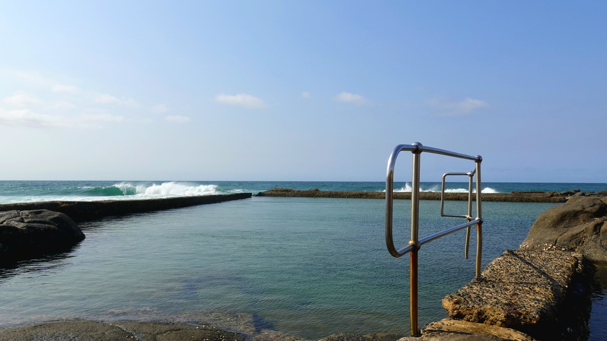 Tranquil coastal rock pool with waves at Ballito, South Africa under a clear blue sky