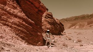 An astronaut in a spacesuit explores a barren, eroded desert, resembling Martian terrain