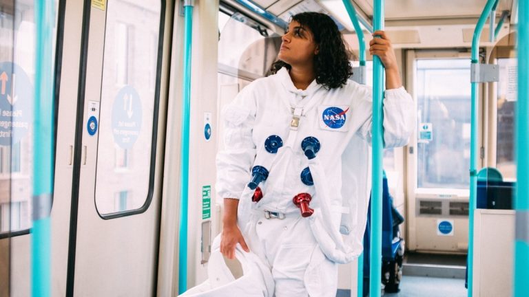 A person in an astronaut suit riding a train, blending sci-fi with everyday life