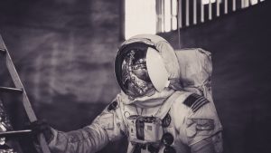 Astronaut in spacesuit climbing ladder inside a dark setting