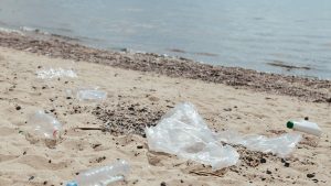 Plastic waste and litter scattered on a sandy beach, highlighting environmental pollution issues