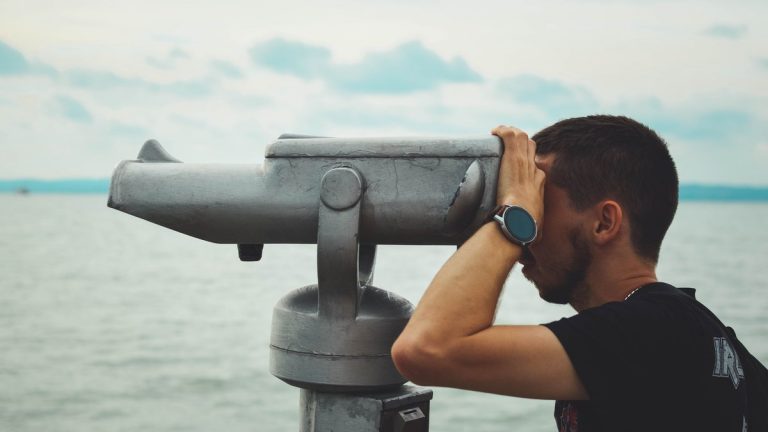 A bird watcher using binoculars beside Lake Balaton