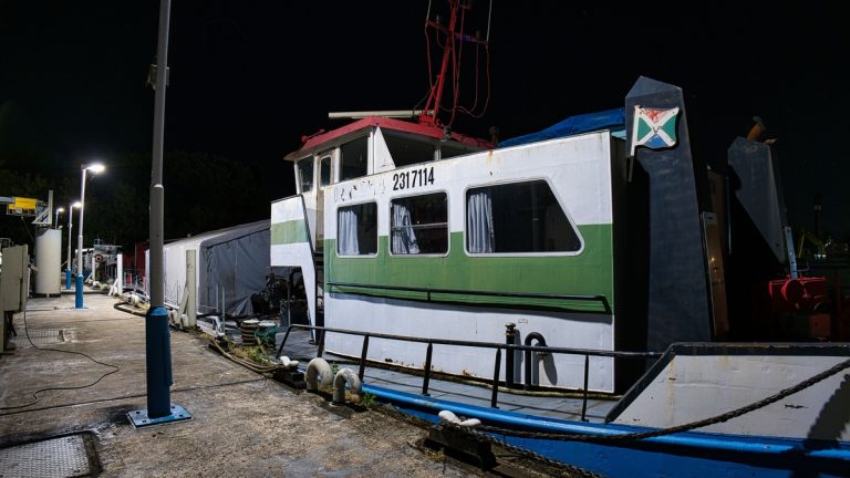 Fishing boat docked at a harbor under street lights at night