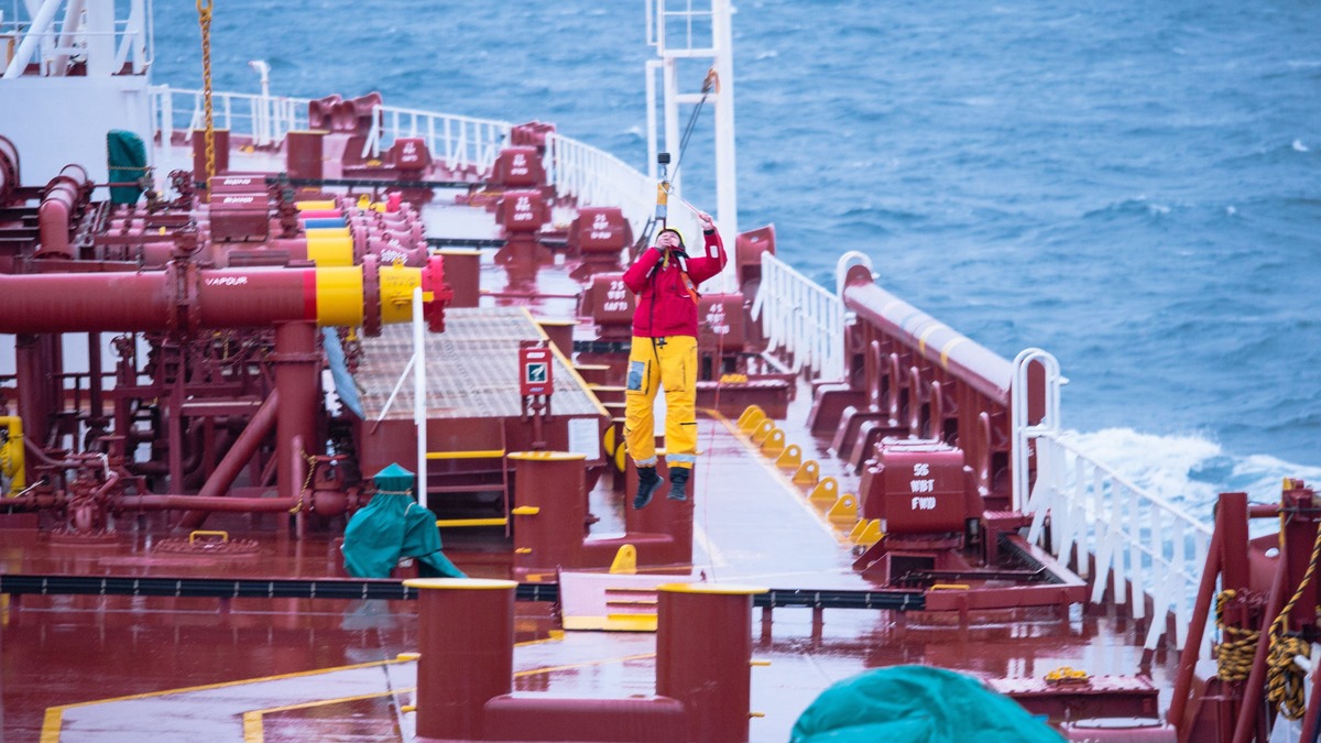 Seafaring crew operating on deck of cargo ship amidst ocean, showcasing teamwork and maritime expertise