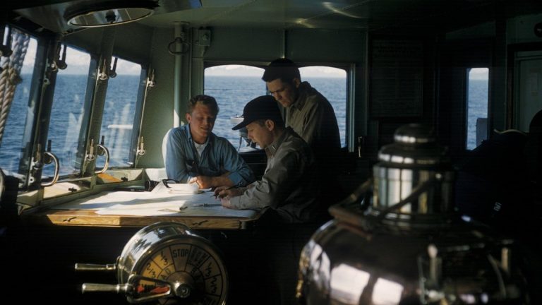 Three seafarers navigating from a ship's bridge