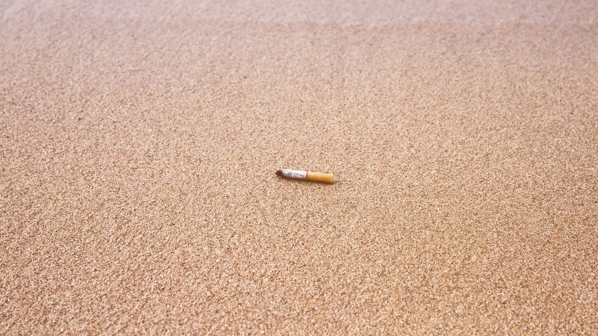 Cigarette butt discarded on a sandy beach, highlighting pollution