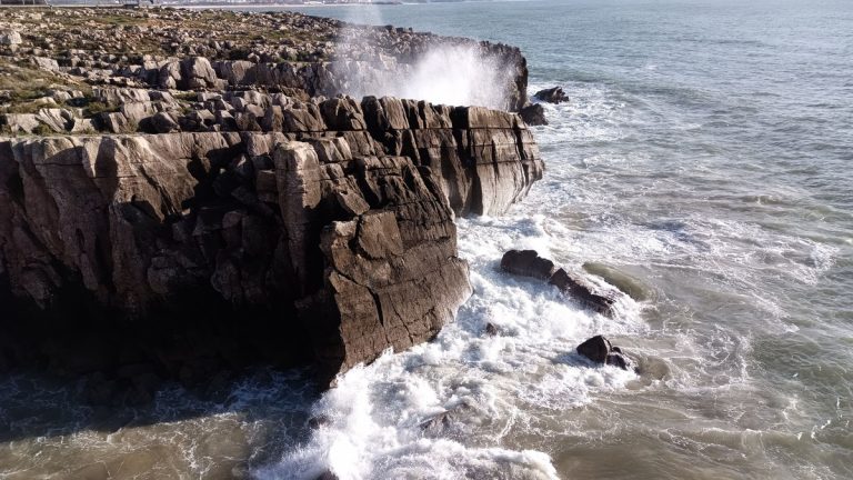 Powerful ocean waves crash into the rugged cliffs of Peniche, Portugal, creating a breathtaking coastal view