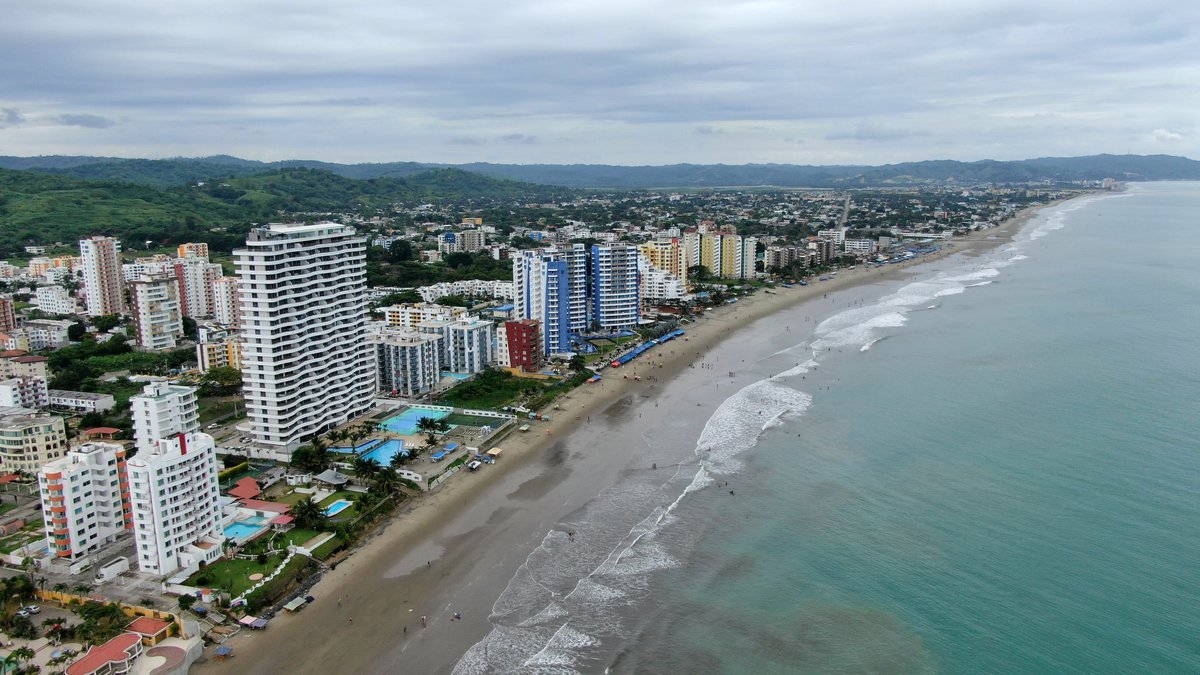 Aerial view of an amazing coastal town on a summer cloudy day. Top view of a town with many hotels, swimming pools, blue beautiful sea and clouds