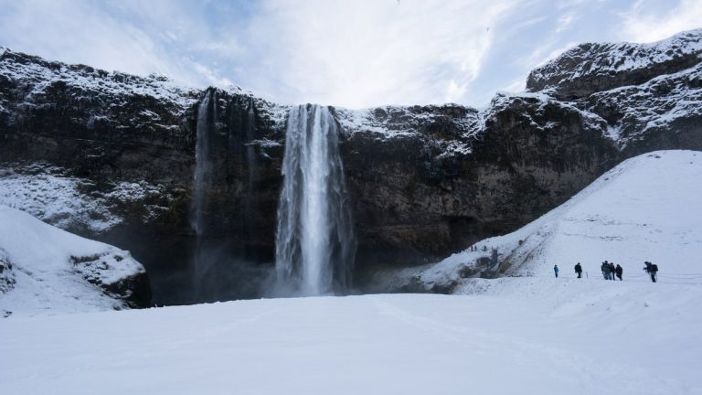 Tourists viewing snow covered landscape and high waterfall, Iceland, Europe. Iceland nature 2017 winter cold