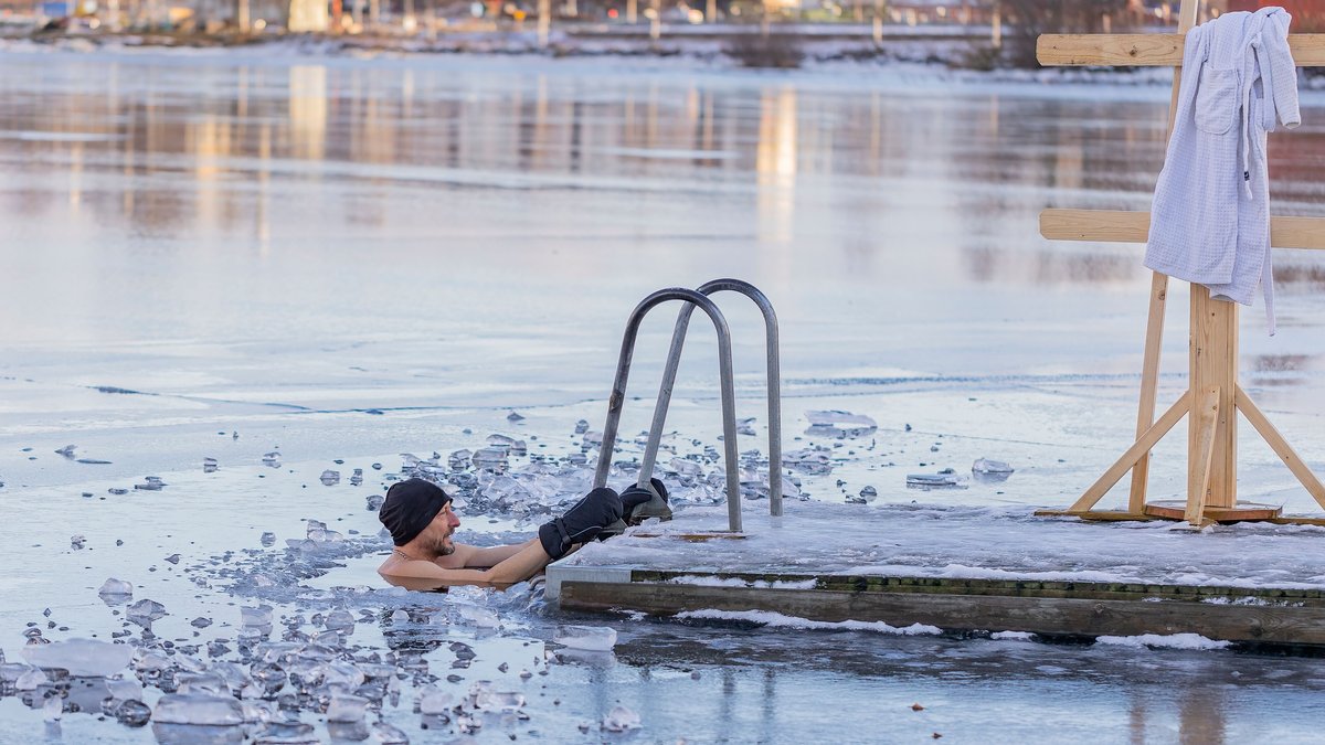 A man taking a winter swim in icy water beside a dock