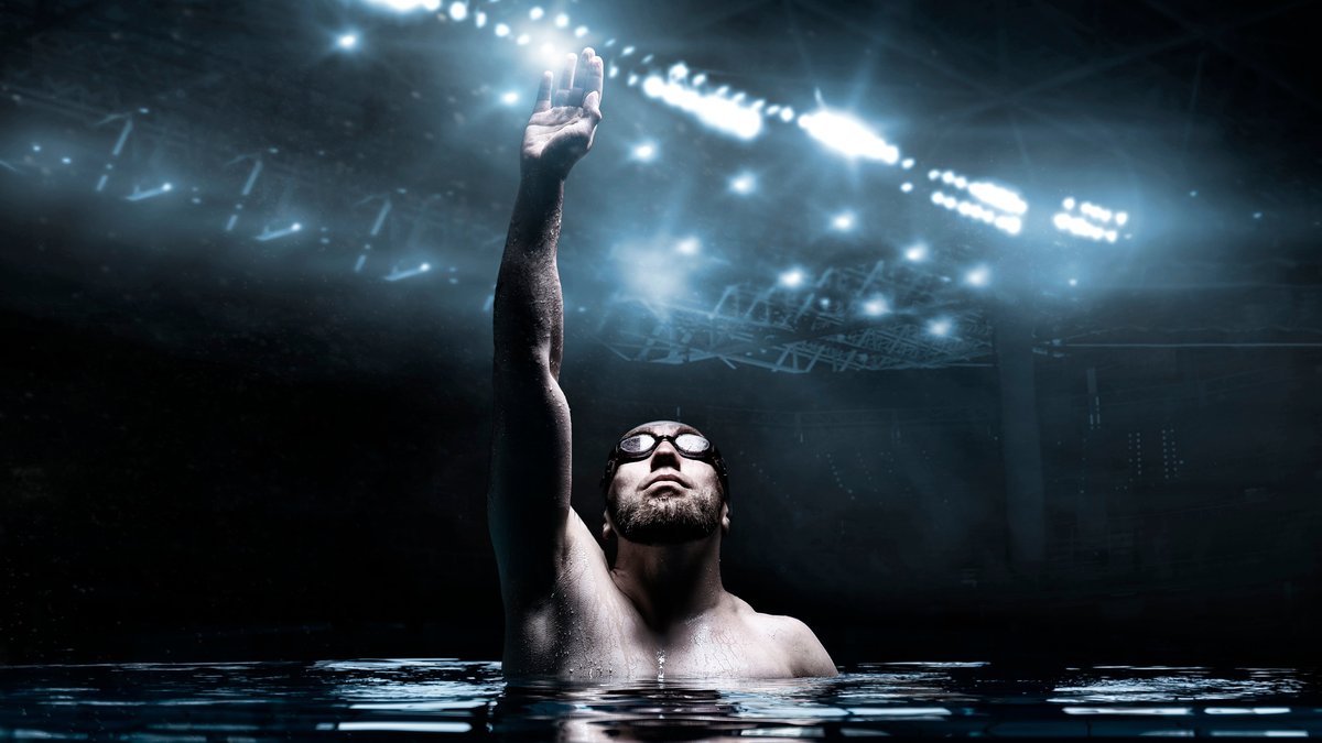Swimmer in the pool raises his hands up. Water Sports Victory Concept. Arena with flashes. Mixed media