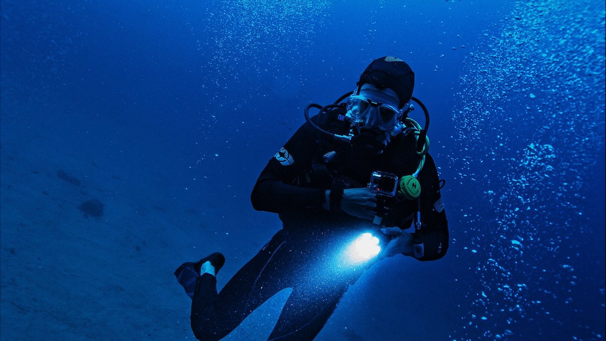 A scuba diver using a light in deep water