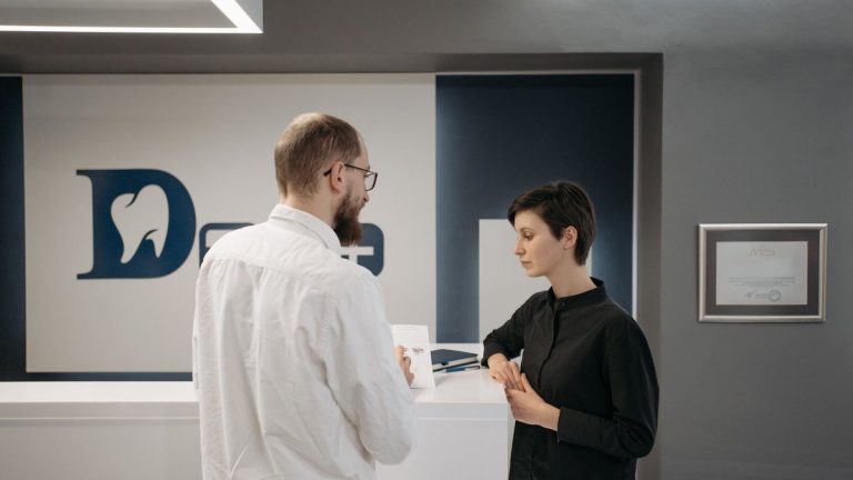 A male dentist consulting a female patient at a modern dental clinic reception