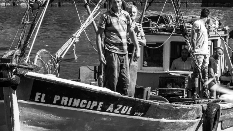 Black and white photo of a boat crew onboard a fishing vessel titled 'El Principe Azul.'